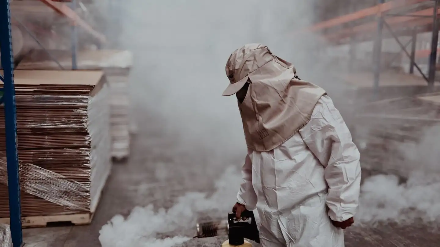 Pest control technician in protective gear treating a property