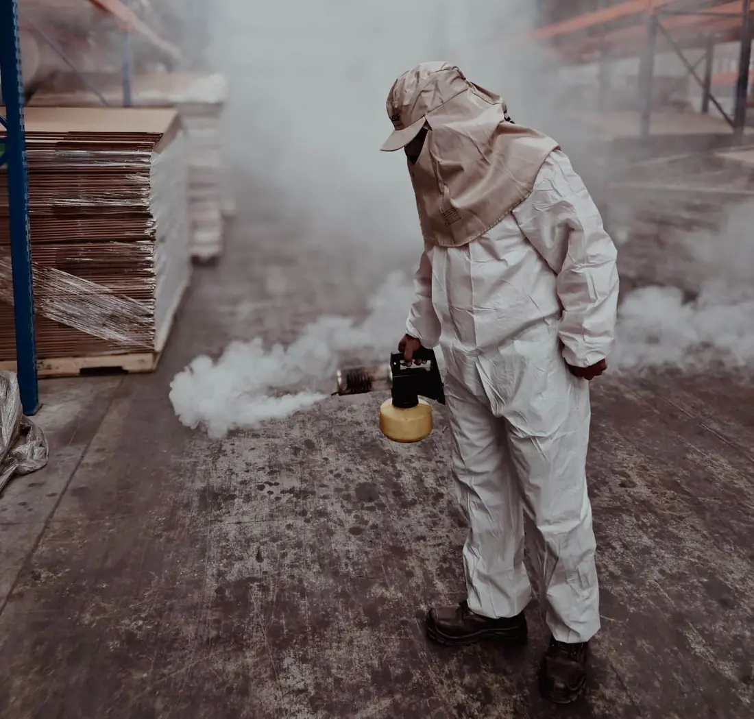 Pest Hunter technician in protective gear fogging a warehouse for pest control